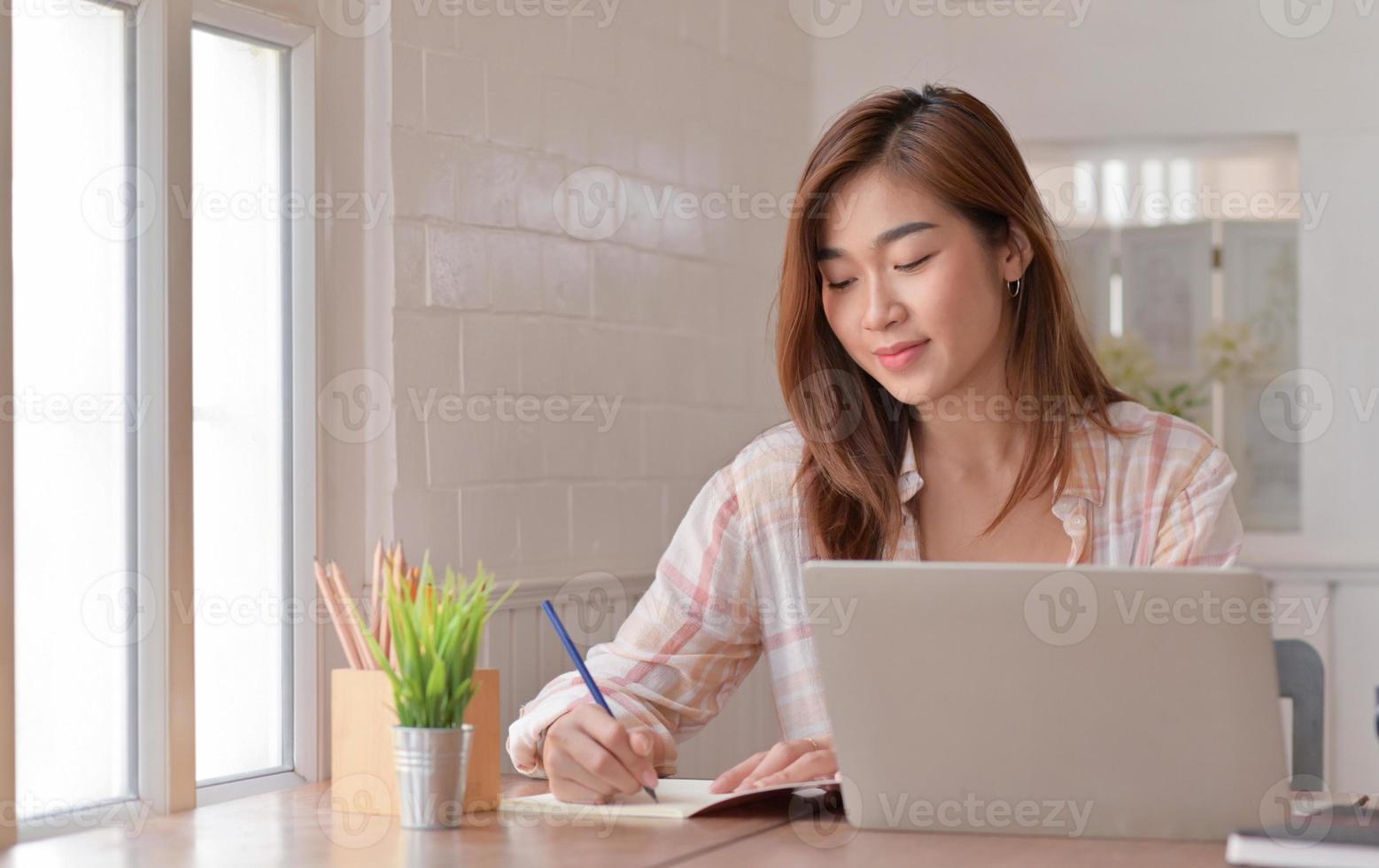 aluna adolescente está tomando notas e estudando online em casa com um laptop. foto