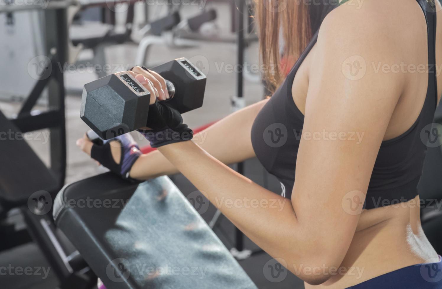 mulher de aptidão levantando halteres na mão. foco na barriga e halteres. foto