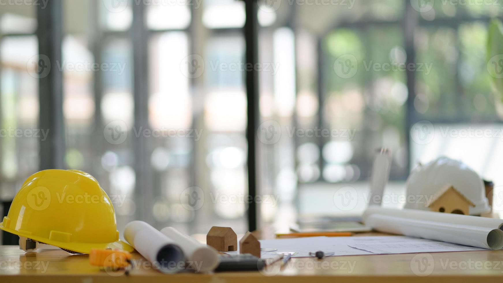 chapéus de segurança e plantas baixas com ferramentas de desenho colocadas na mesa do escritório do arquiteto. foto