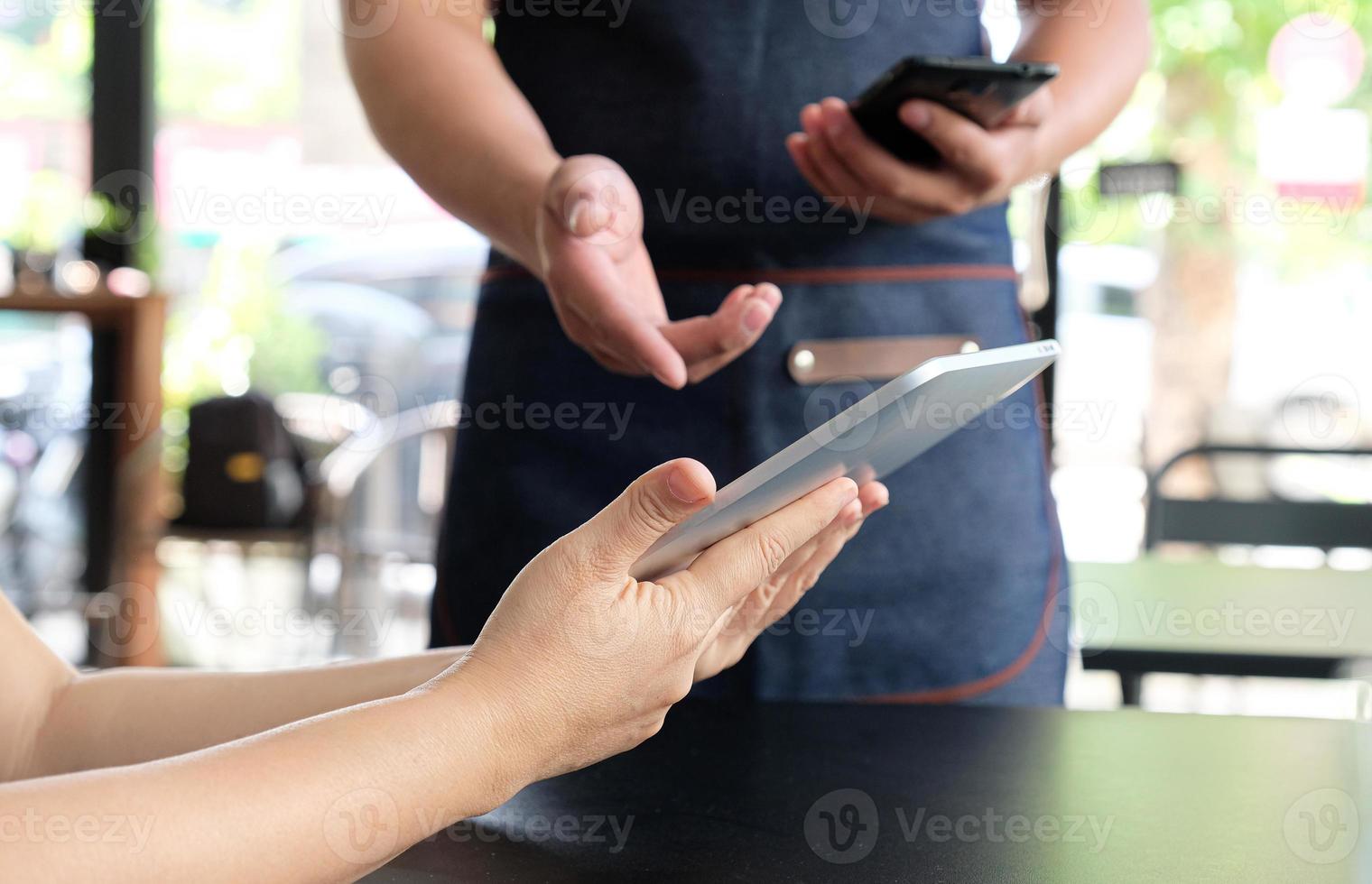 funcionário segurando um smartphone para salvar o menu do pedido do cliente. foto