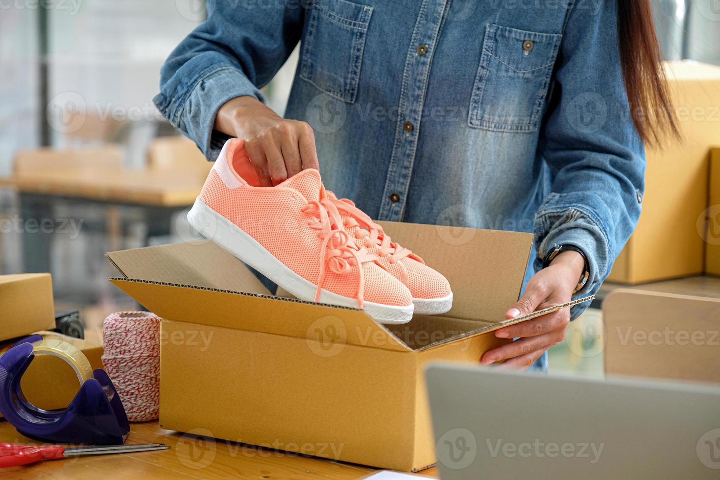 vendedores online estão embalando sapatos em caixas para entregar aos clientes. foto