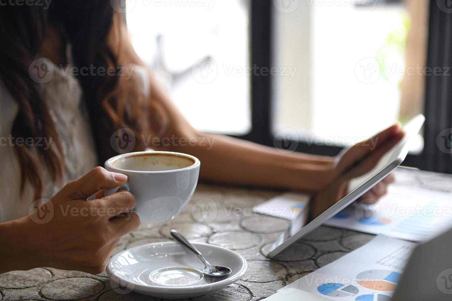 mulher executiva bebe café e usa tablet durante o intervalo. ela sentou-se perto da janela no escritório. foto