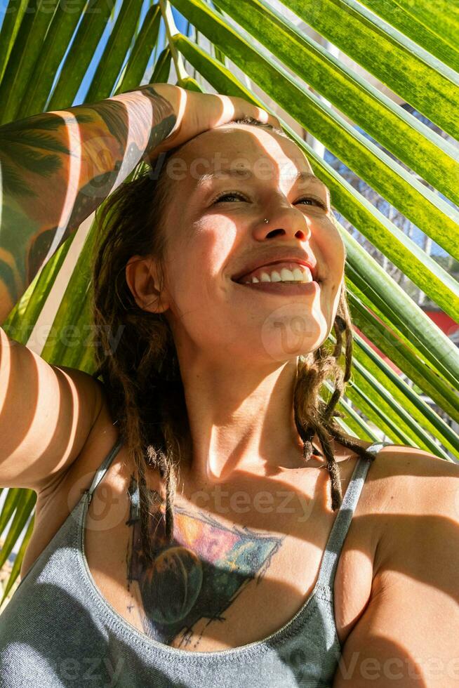 sorridente mulher levando selfie debaixo Palma folha em tropical de praia. verão Férias momento. foto