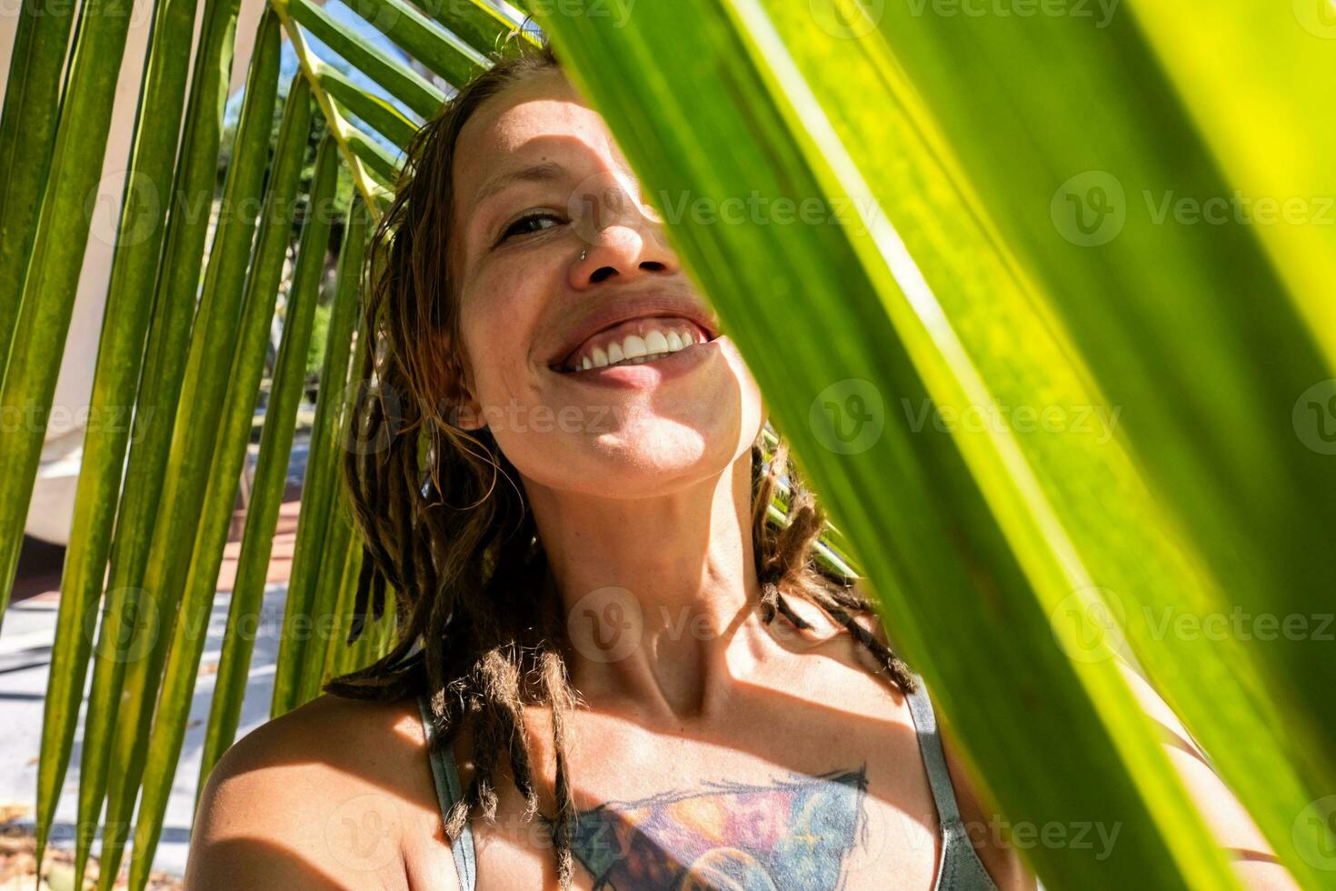 sorridente mulher levando selfie debaixo Palma folha em tropical de praia. verão Férias momento. foto