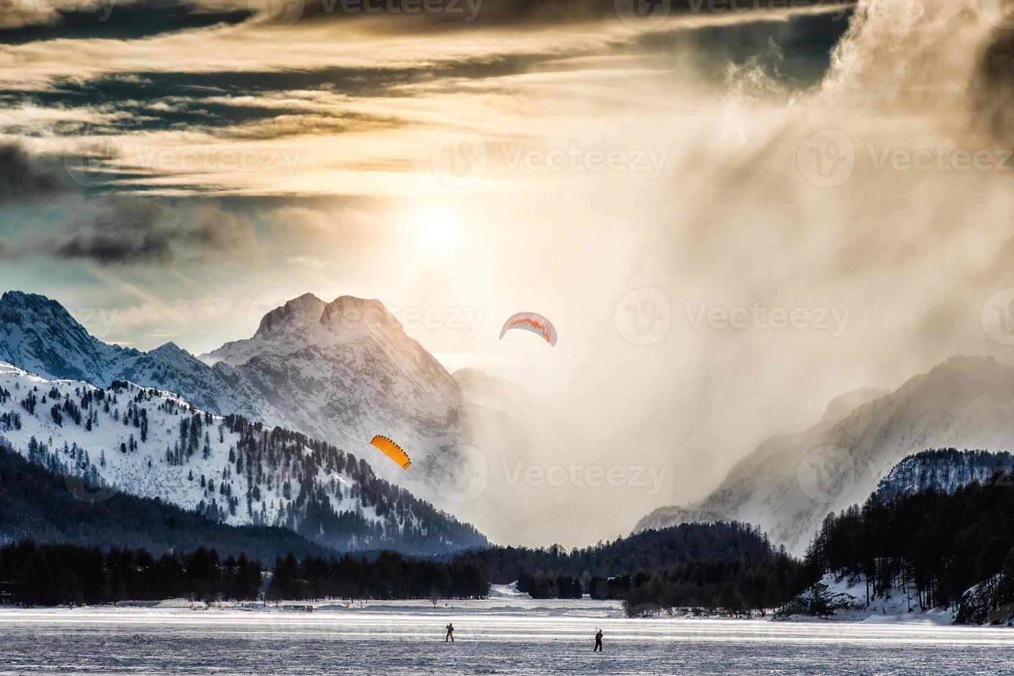 dois kitesurf em um lago congelado nas altas montanhas foto