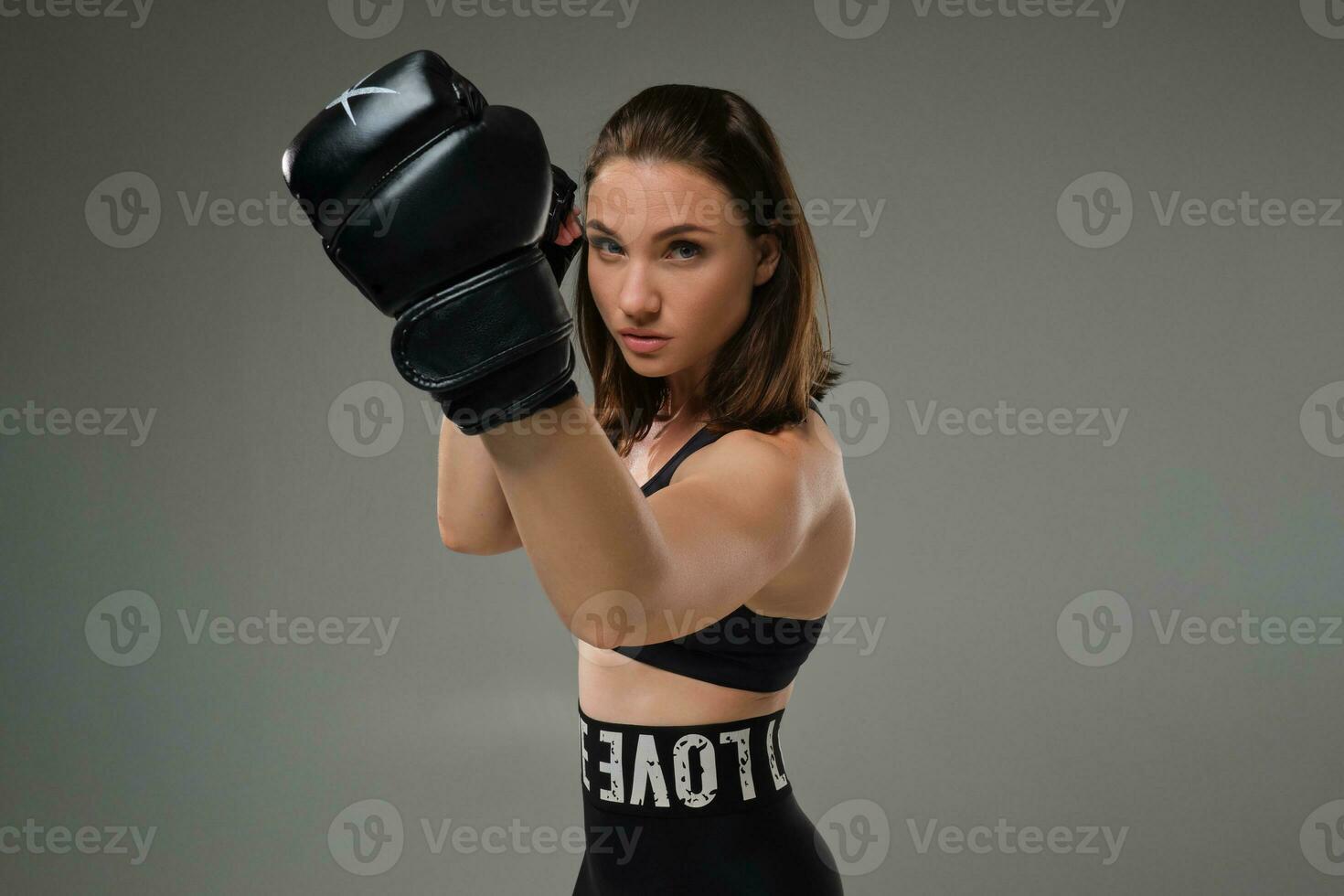 Atlético mulher dentro boxe luvas é praticando karatê dentro estúdio. foto