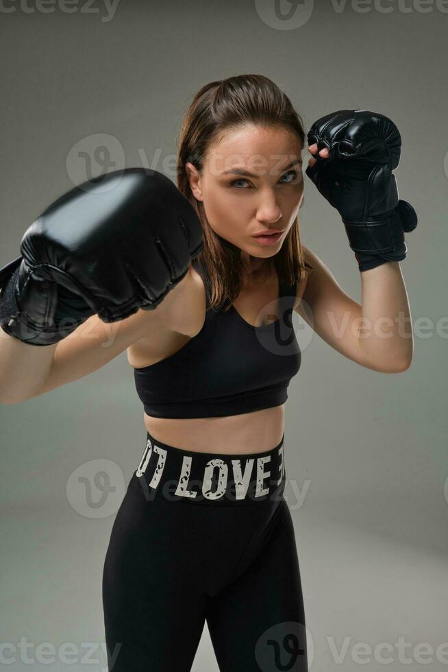 Atlético mulher dentro boxe luvas é praticando karatê dentro estúdio. foto