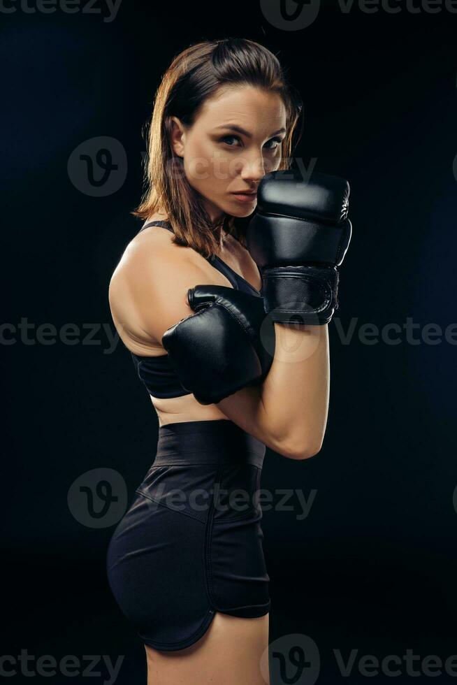 Atlético mulher dentro boxe luvas é praticando karatê dentro estúdio. foto