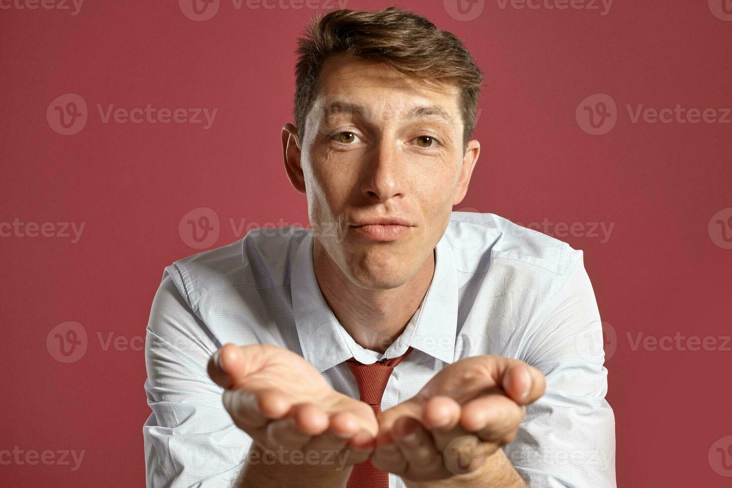 retrato do uma jovem moreno homem posando dentro uma estúdio contra uma vermelho fundo. foto