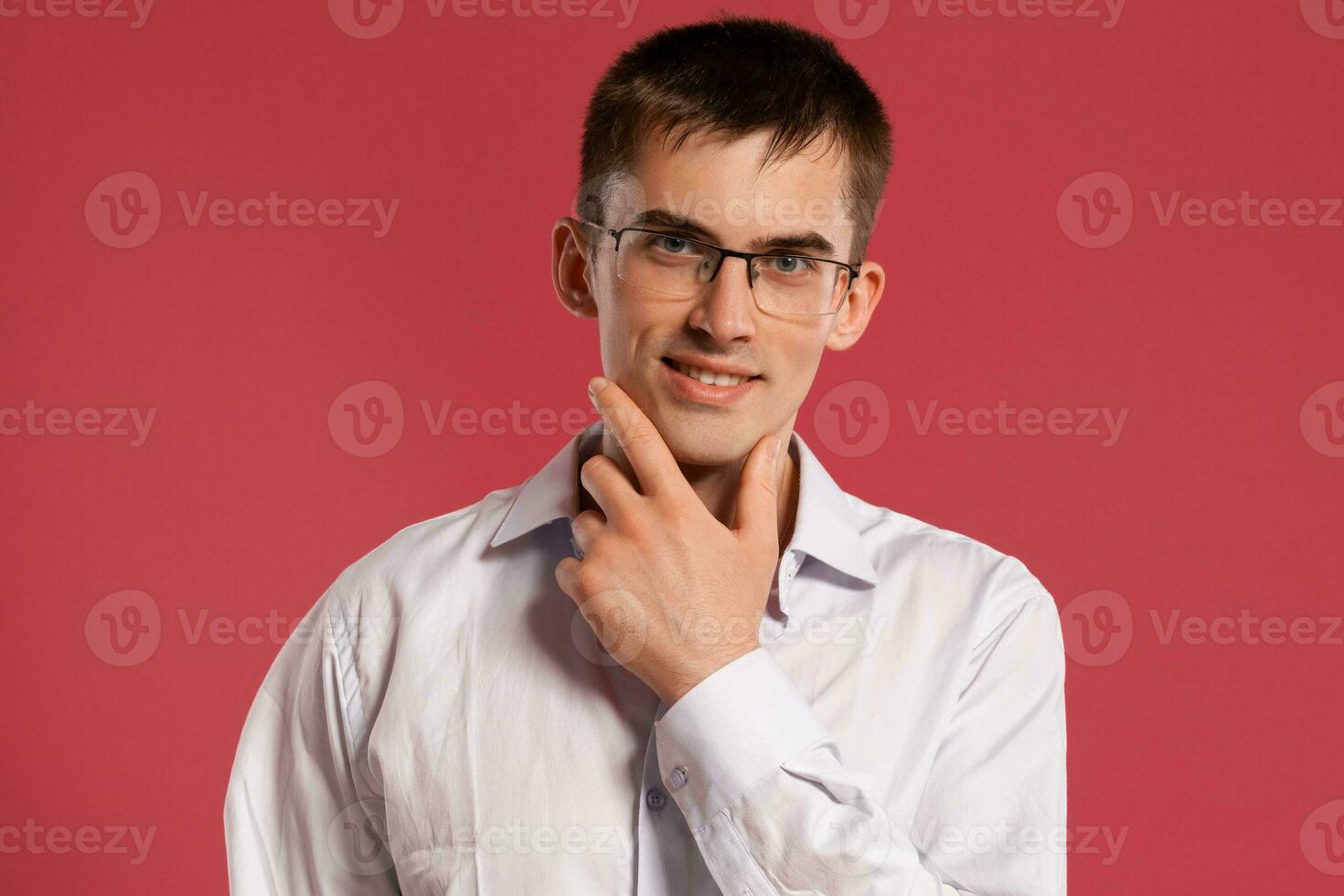 jovem homem dentro uma clássico branco camisa é posando sobre uma Rosa fundo. foto