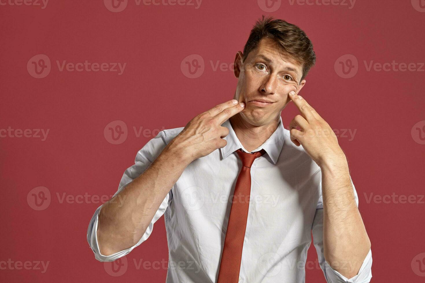 retrato do uma jovem moreno homem posando dentro uma estúdio contra uma vermelho fundo. foto