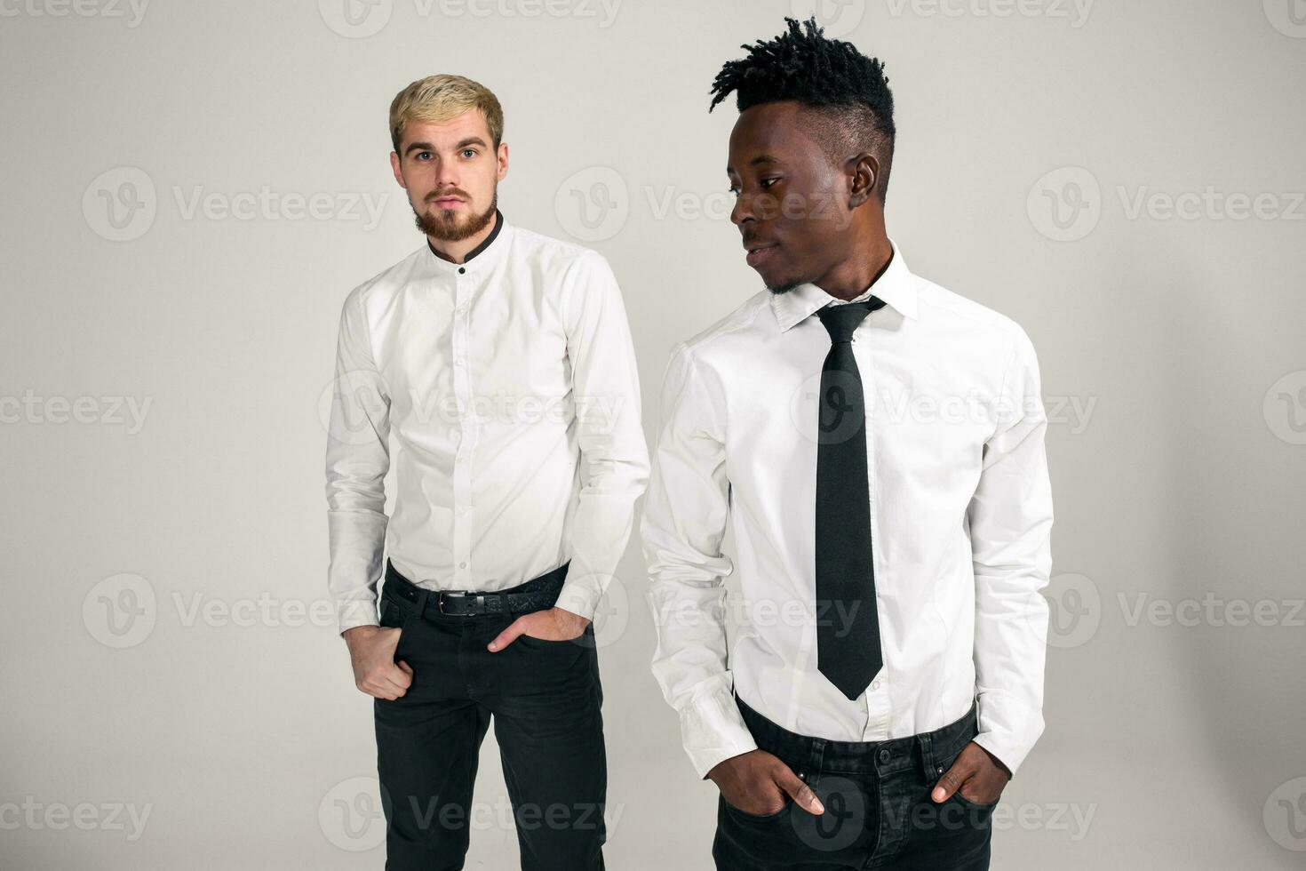 internacional amizade conceito. estúdio tiro do dois à moda jovem homens em branco fundo foto