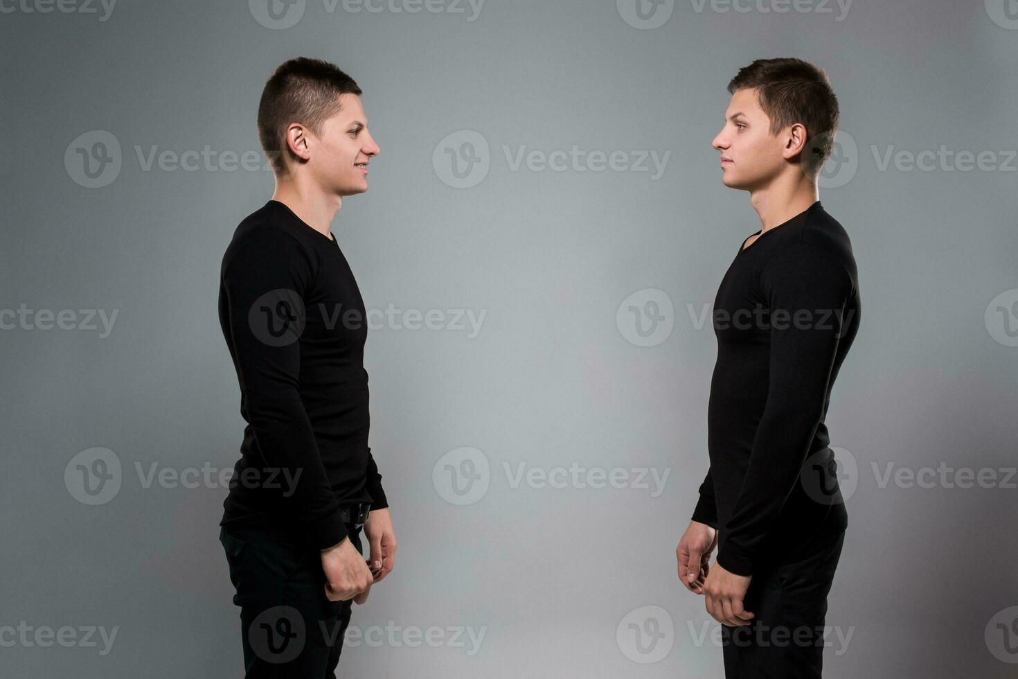 retrato do jovem gêmeo irmãos em pé face para face em cinzento BA foto