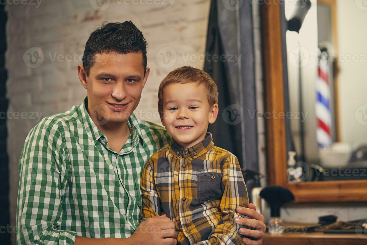 jovem bonito pai e dele pequeno à moda filho às barbearia esperando para barbeiro foto