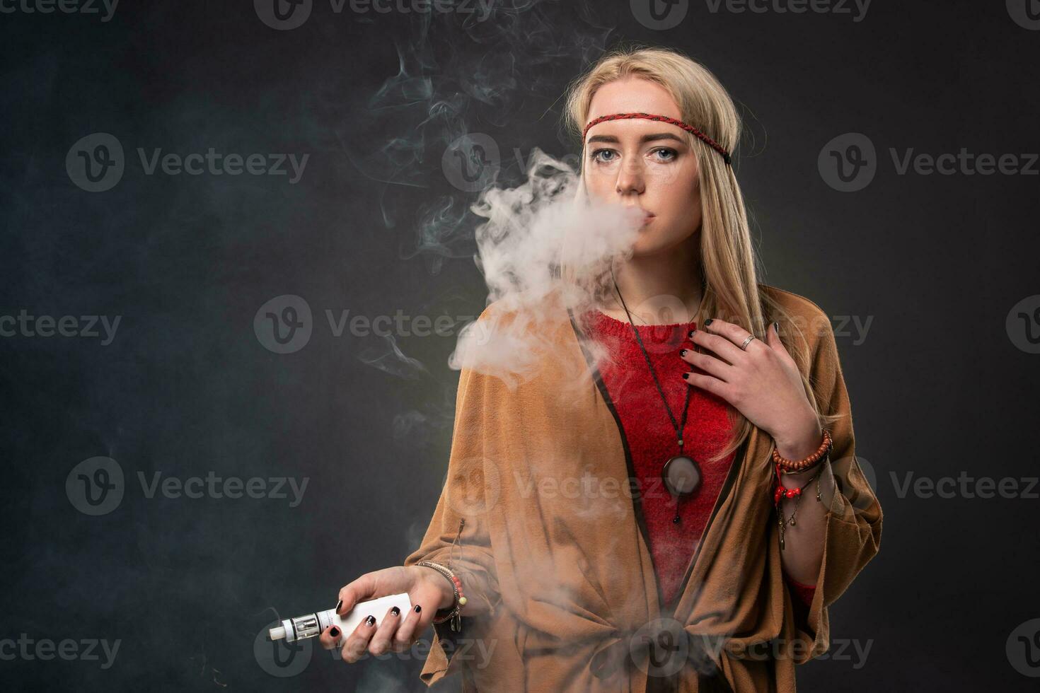 retrato do sexy jovem hipster fumar Cigarro eletrônico garota. a mulher é vestido dentro a estilo do uma boho. vapor conceito. Cigarro eletrônico e-cigarro. foto
