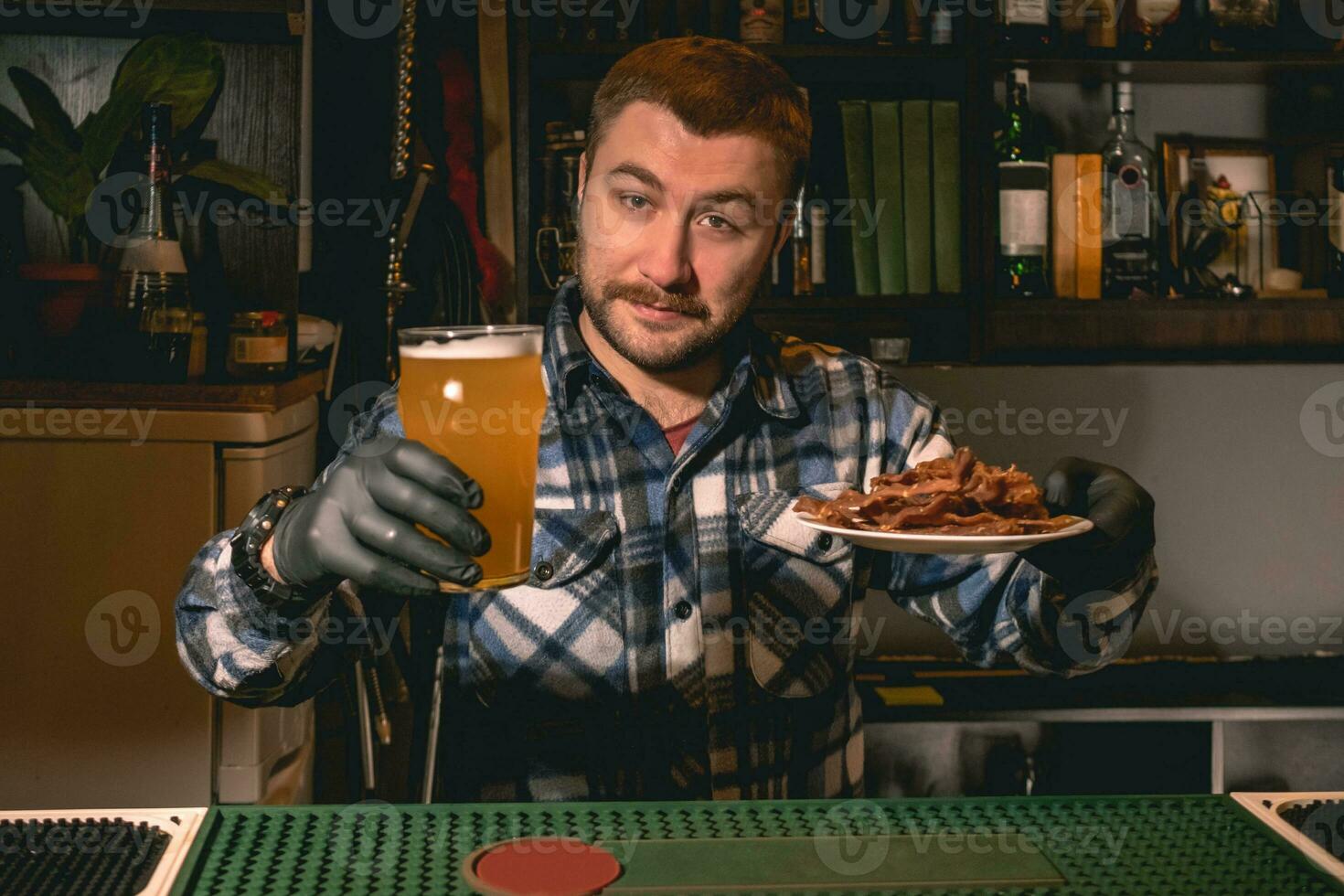 amigáveis barbudo barman oferta vidro do Cerveja com lanches dentro bar foto