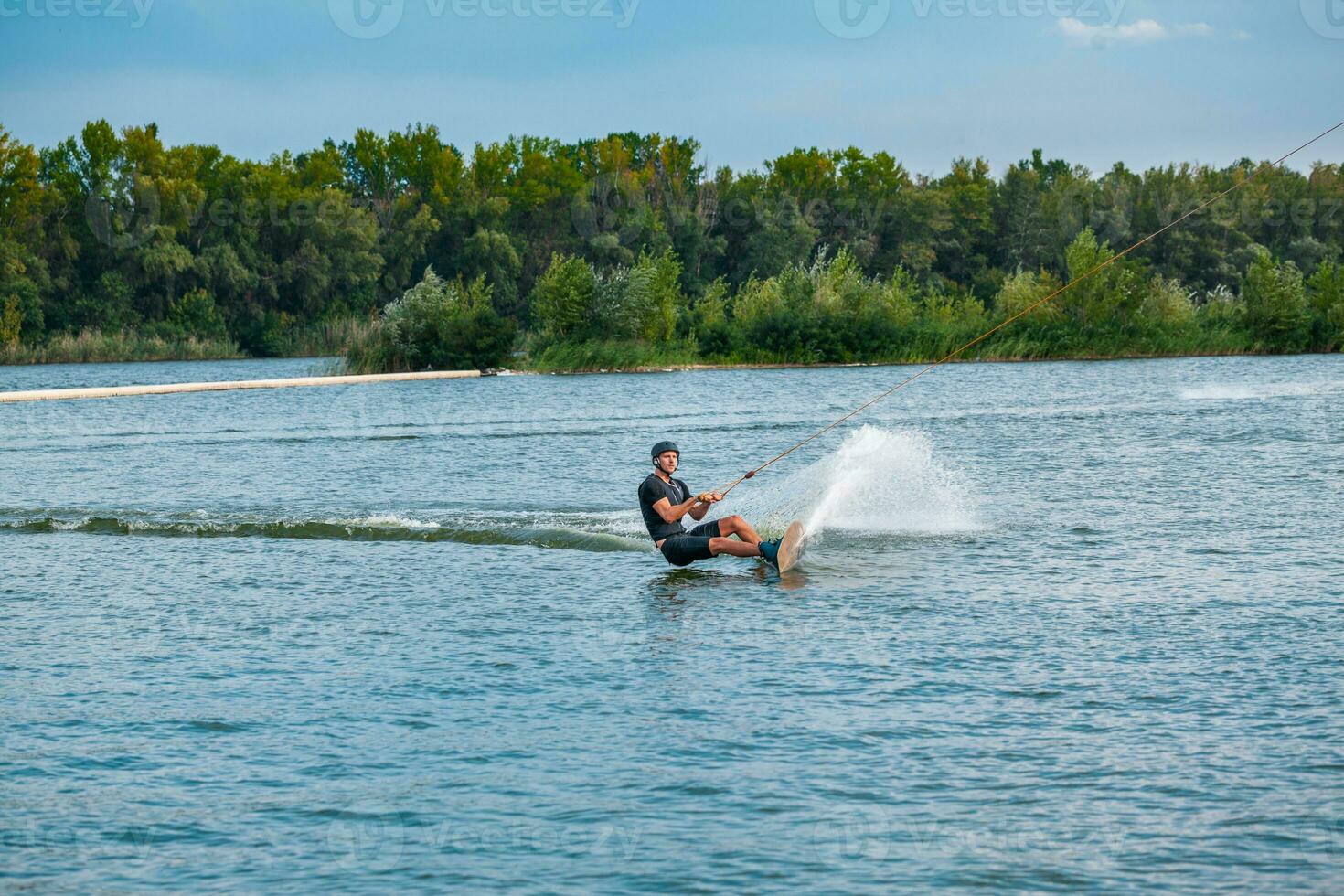 hábil praticante de wakeboard corte água com Beira do borda criando salpicos foto