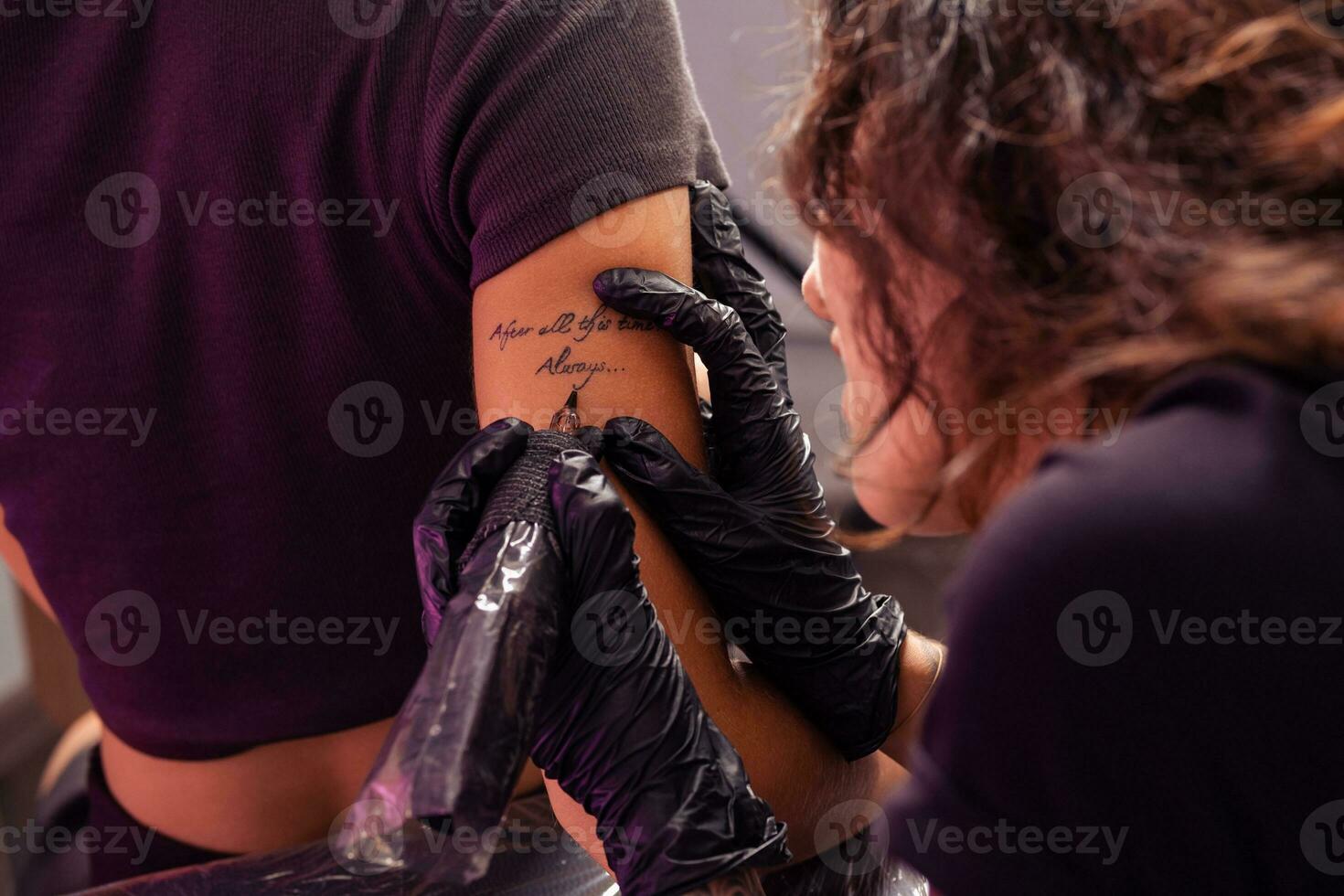 talentoso artista construindo personalizado letras tatuagem em fêmea braço foto