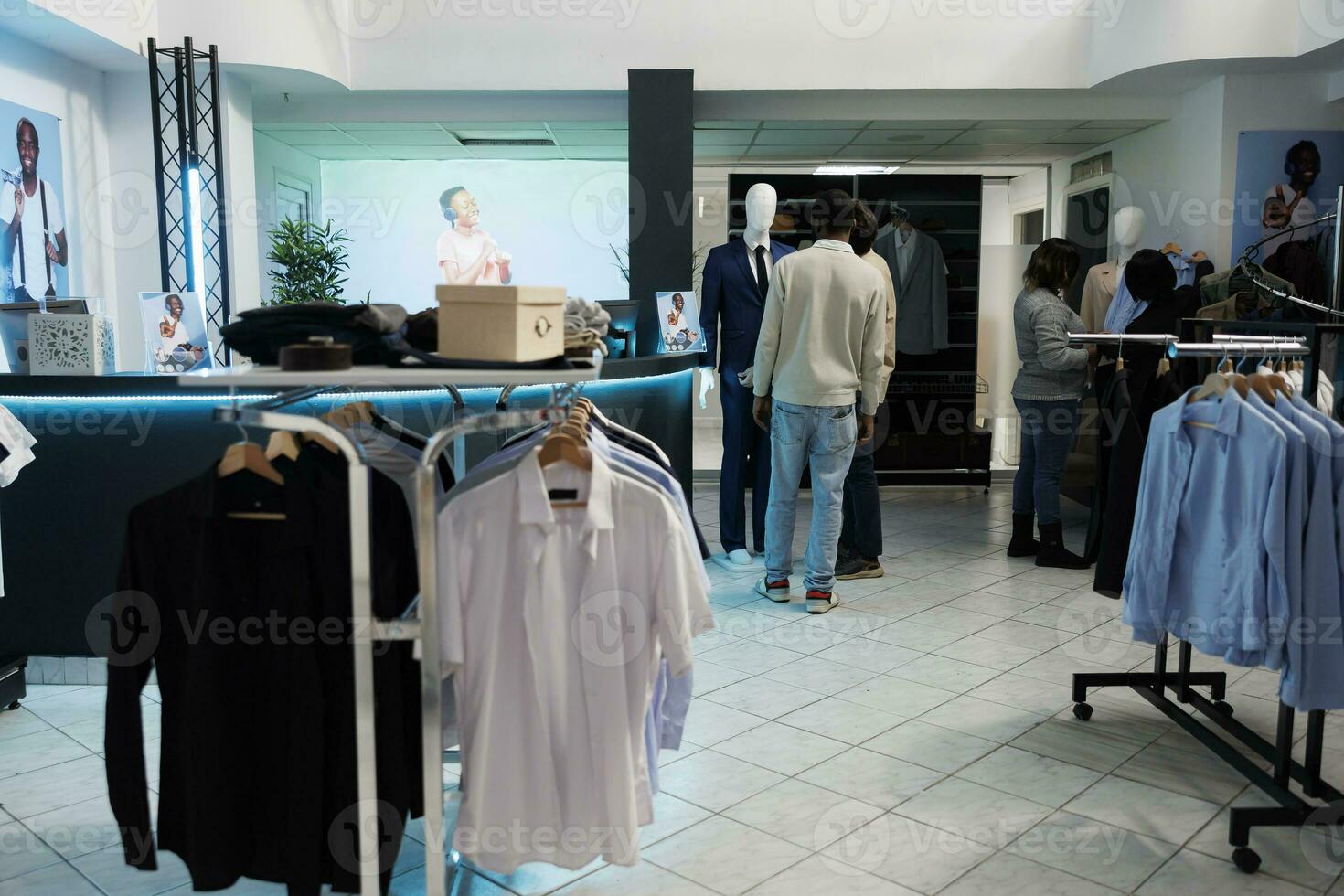 roupas loja cliente e assistente examinando formal terno em manequim. moda sala de exposições cliente obtendo recomendação a partir de assistente enquanto compras para elegante equipamento foto