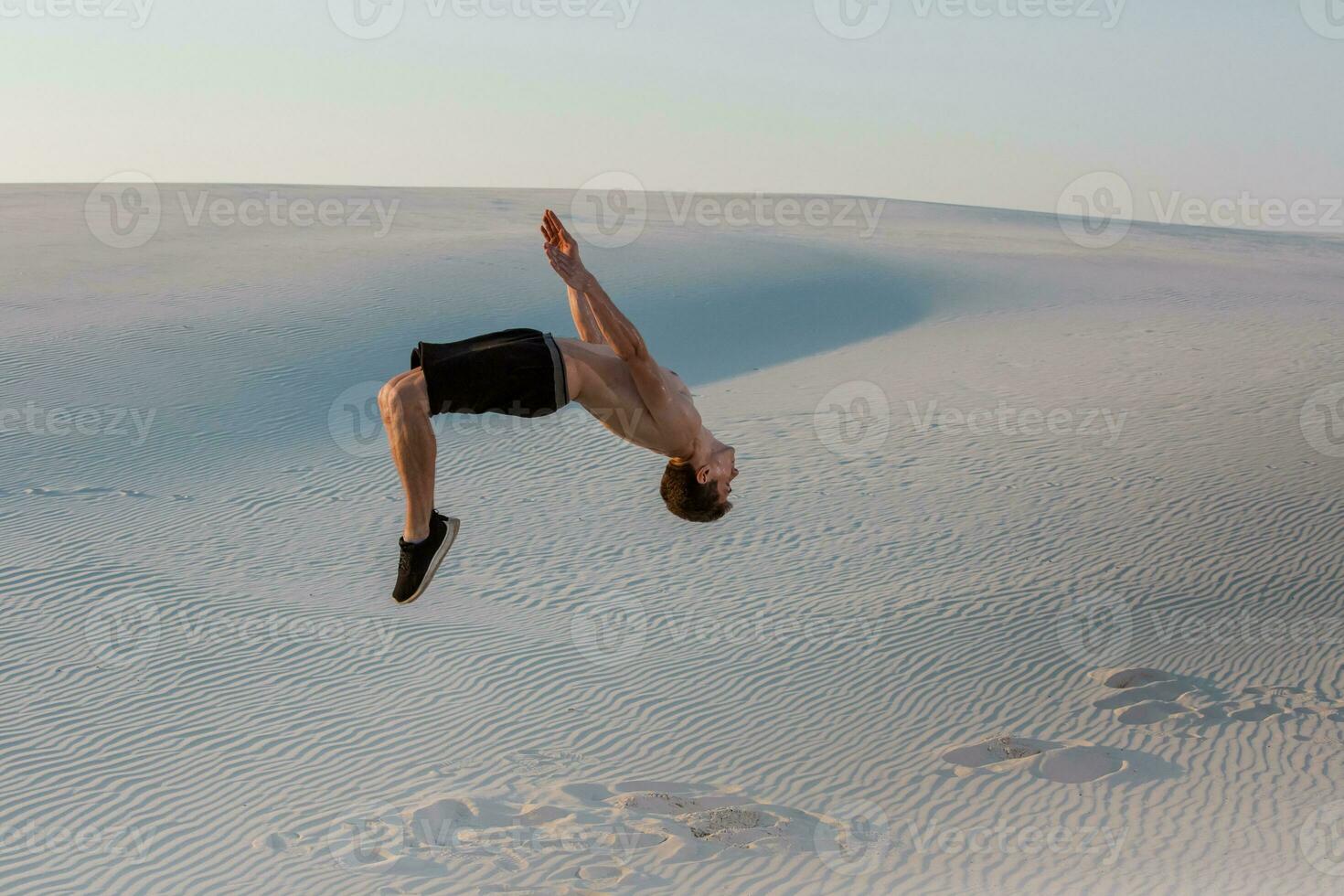 homem estude Parkour em seus ter. acrobacia dentro a areia foto