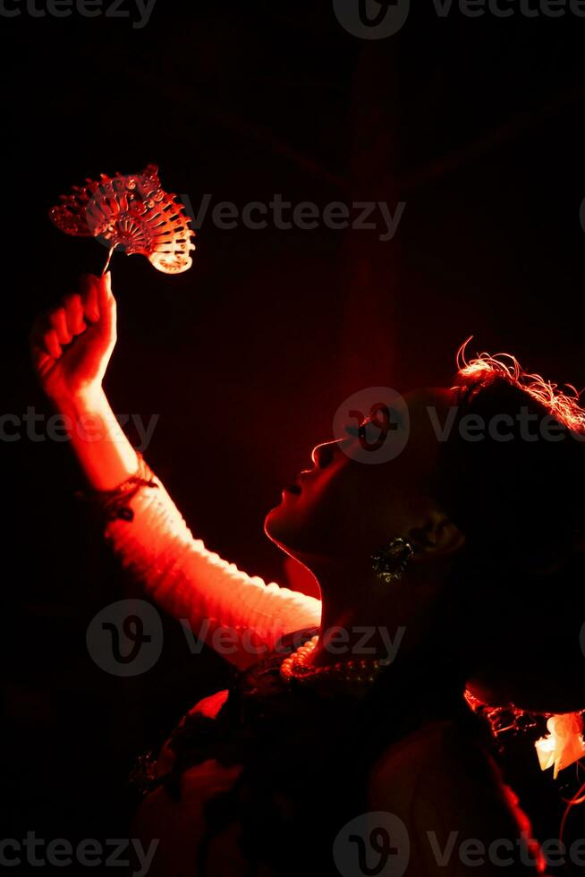 a silhueta do uma fêmea dançarino segurando joalheria este parece gostar uma reflexão refletindo dentro a escuro luz foto