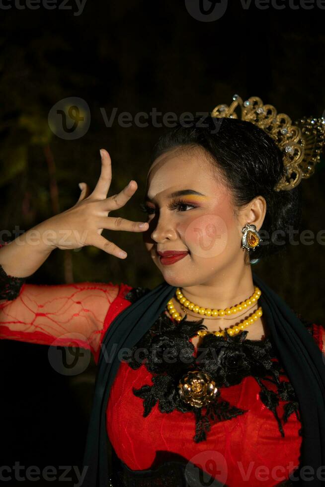 uma javanese dançarino vestindo uma Preto xaile e jasmim em dela cabeça enquanto dançando em etapa às noite foto