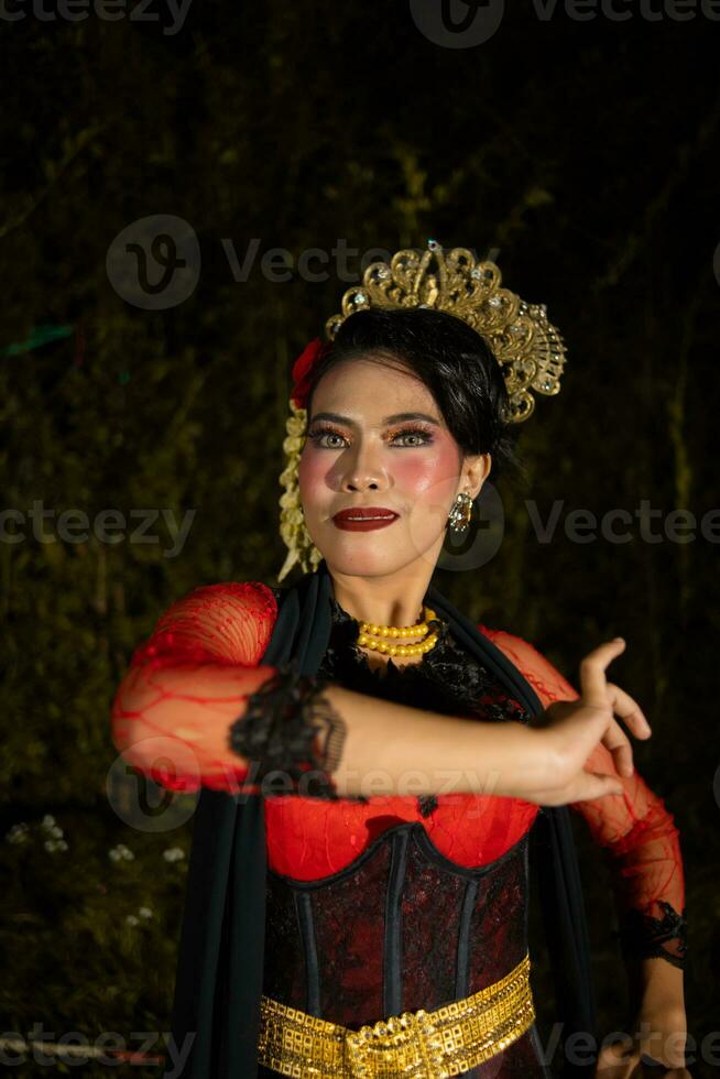 a indonésio dançarino dentro vermelho roupas e uma Preto cachecol poses com muito encaracolado e lindo dedos foto