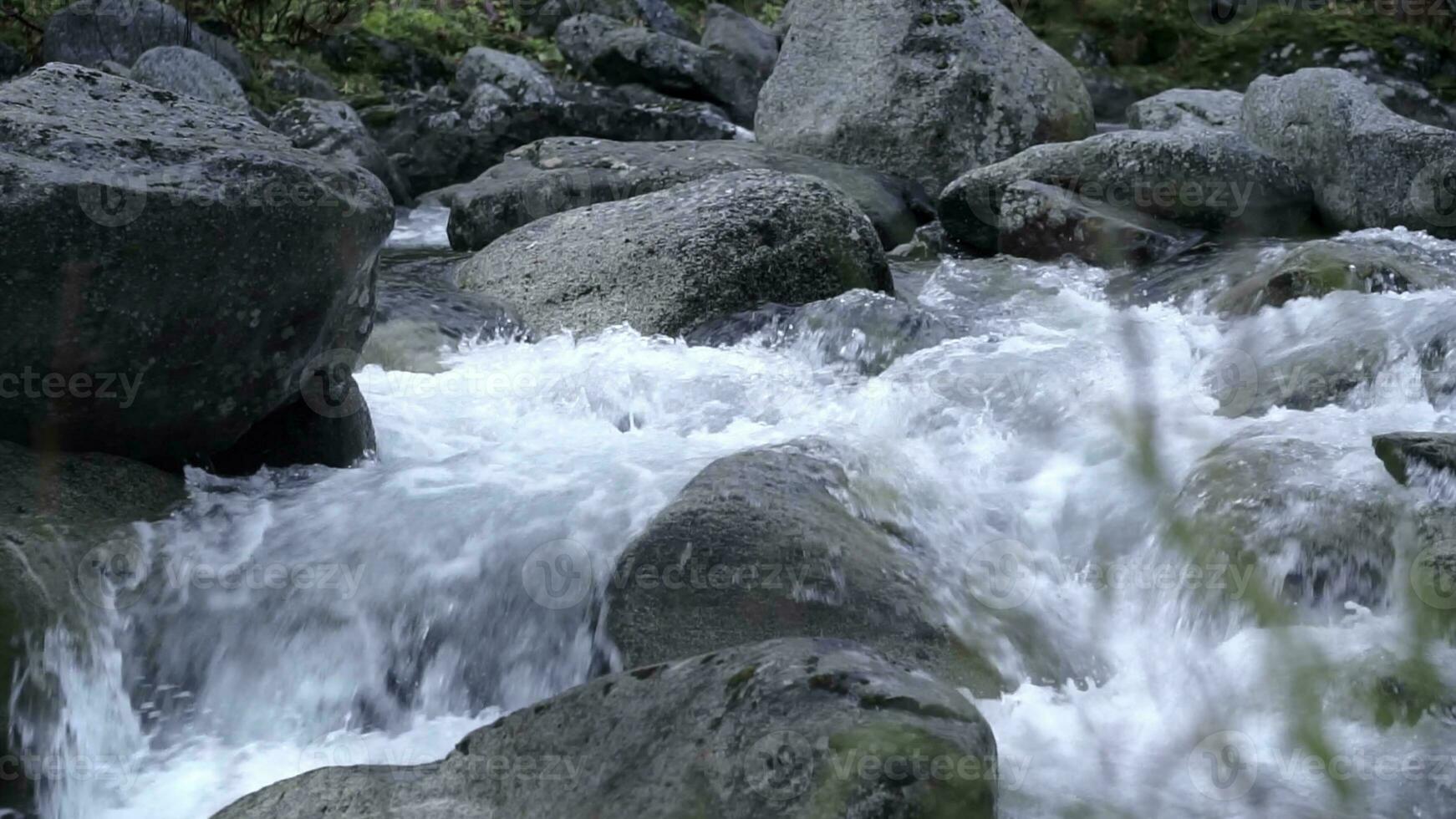 uma enorme jato do água. grampo. Claro frio água espancamento contra cinzento enorme pedras . foto