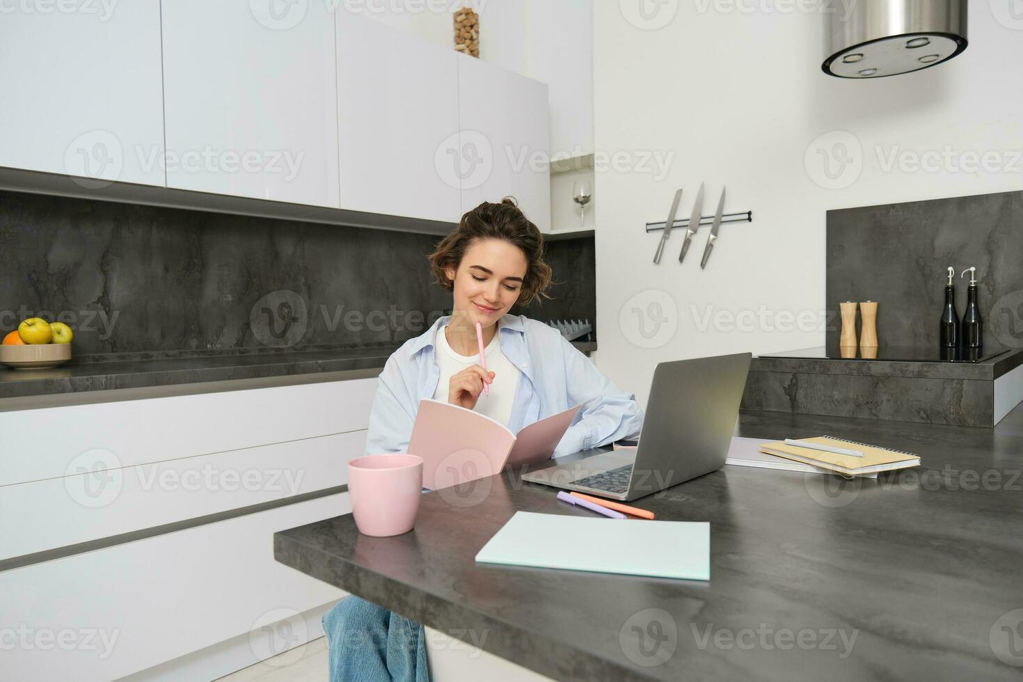 retrato do jovem lindo mulher, estudos às lar, vira dela pasta de trabalho, trabalho a partir de lar, usa computador portátil para aprender em controlo remoto, faz notas durante webinar foto