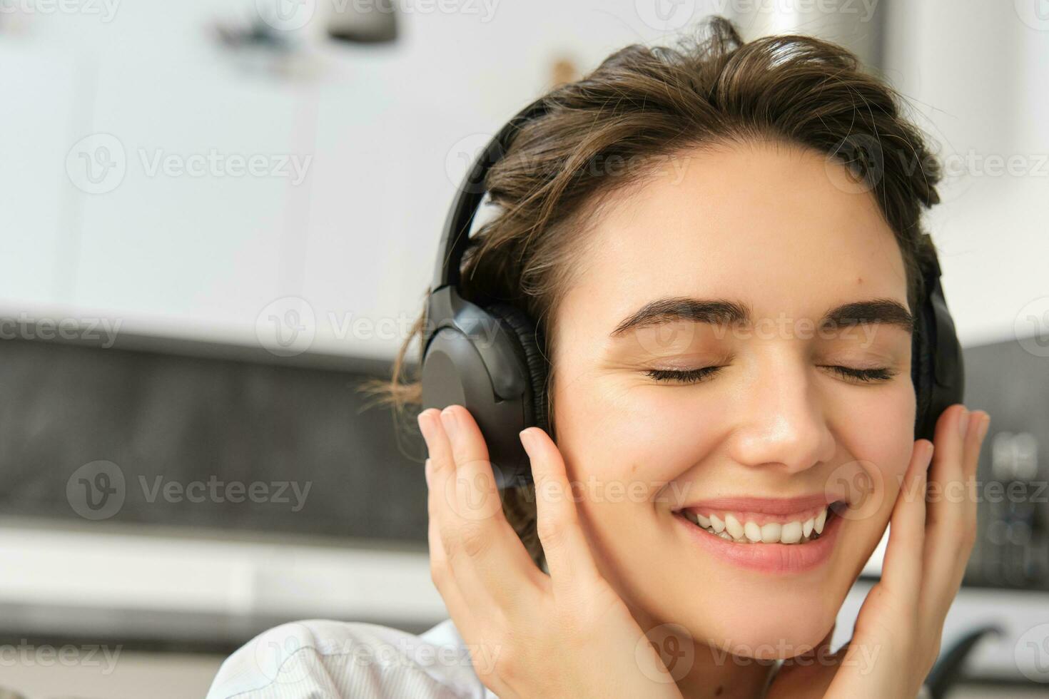 fechar acima retrato do fofa jovem mulher, sorridente e ouvindo para música dentro sem fio fones de ouvido, desfrutando Boa som qualidade foto