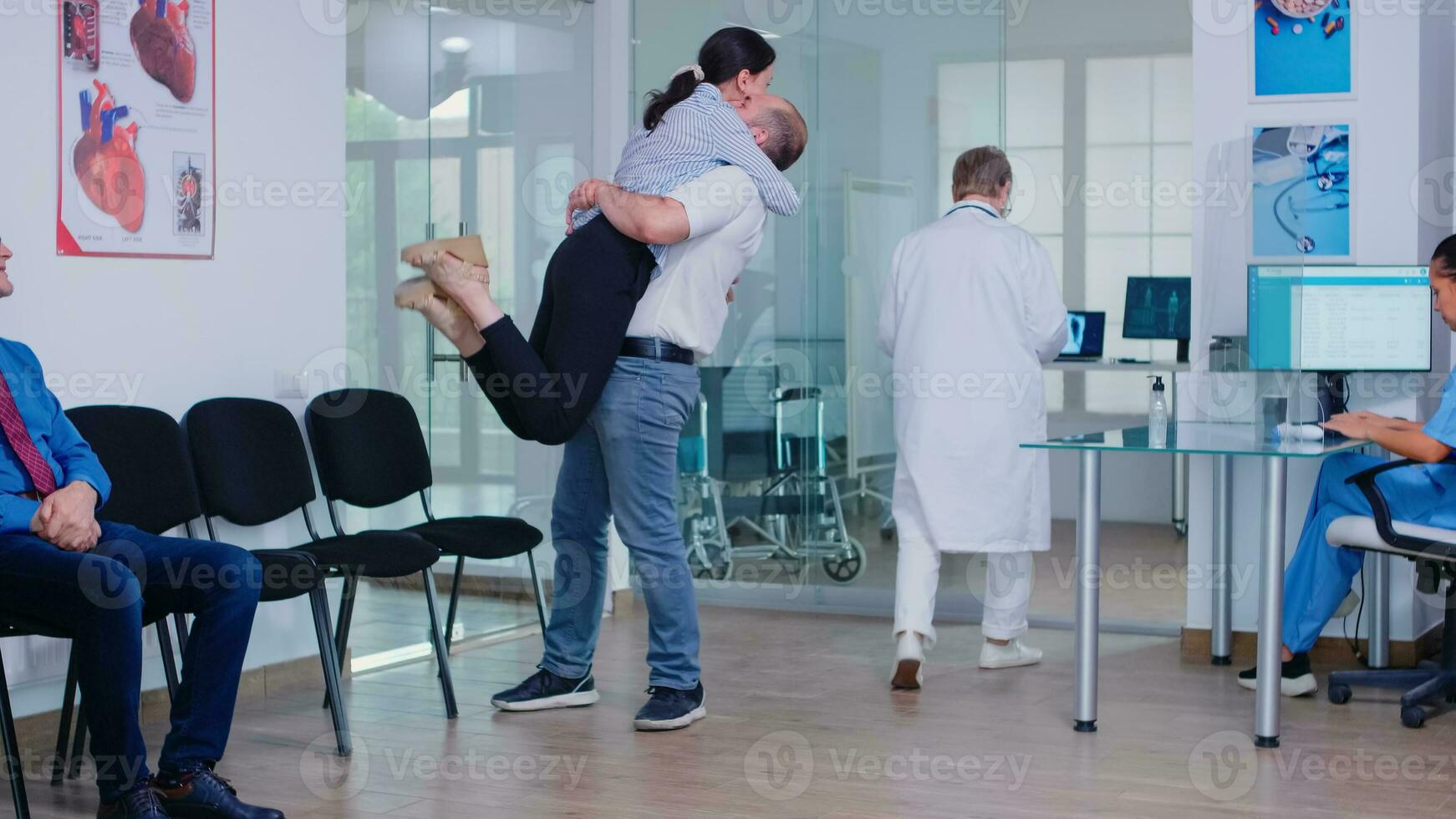 marido abraçando esposa depois de recebendo Boa notícia a partir de médico dentro hospital esperando área. médico vestindo branco casaco e estetoscópio. foto