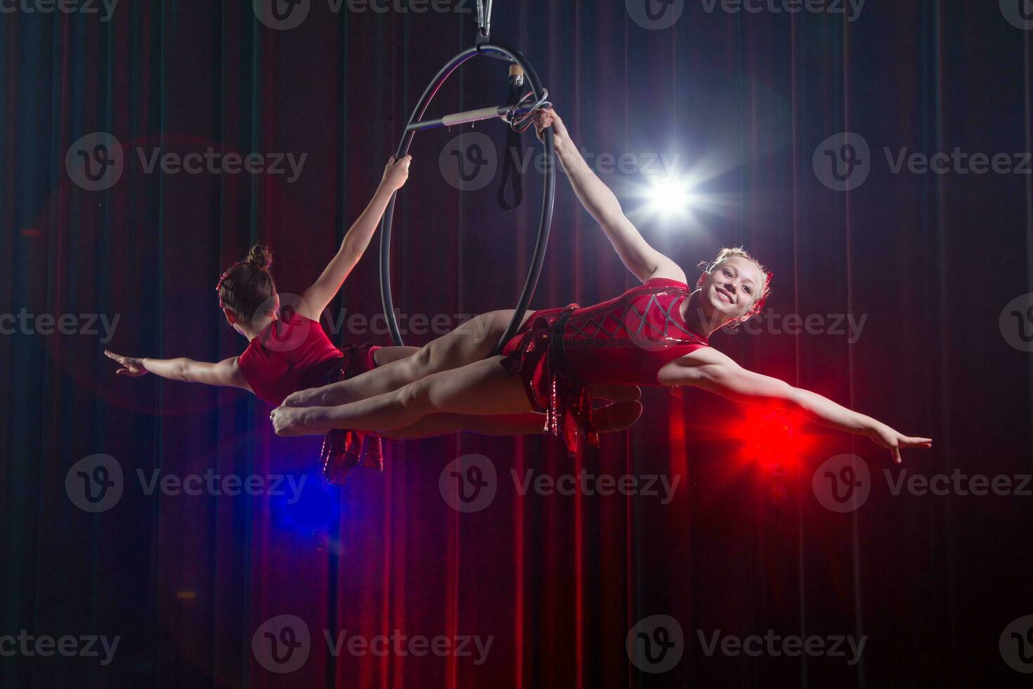 circo atriz acrobata desempenho. dois meninas executar acrobático elementos dentro a ar anel. foto