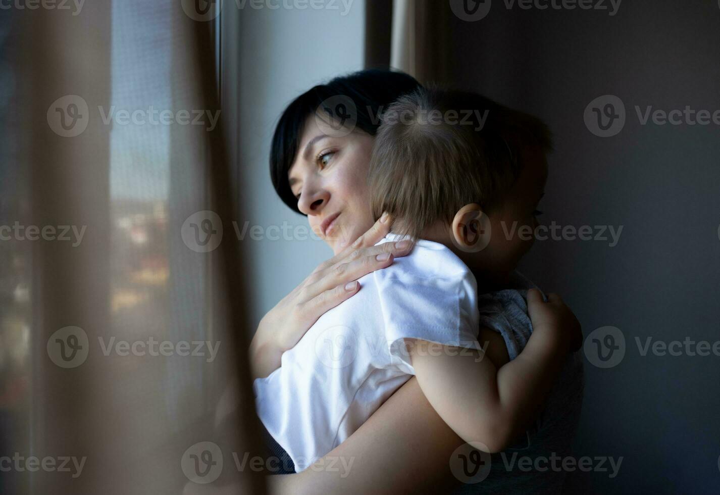 pequeno Garoto com dele jovem lindo mãe Veja Fora a janela foto