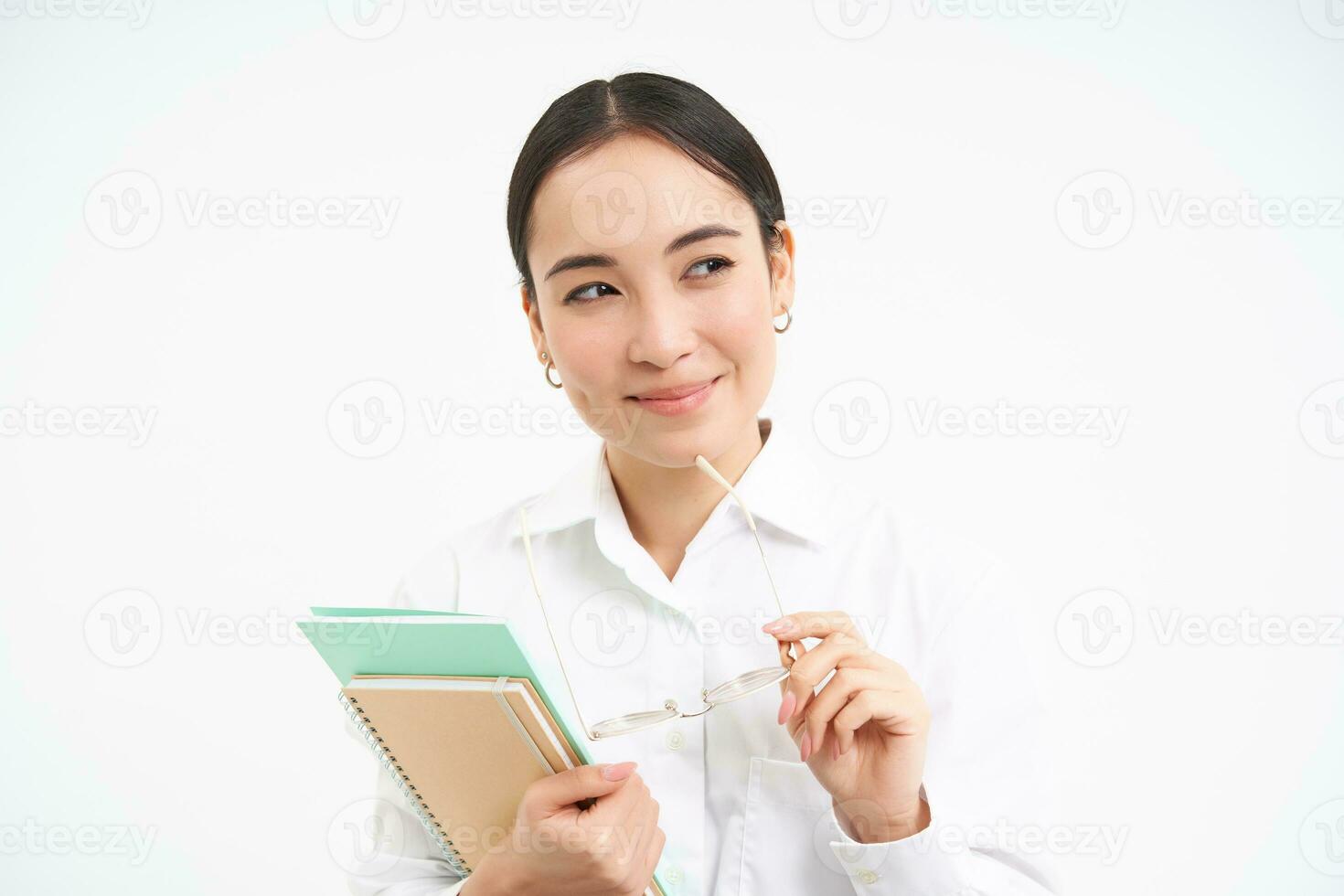 confiante jovem mulher, escritório trabalhador com copos, detém cadernos, parece considerado, pensamento, em pé isolado em branco fundo foto