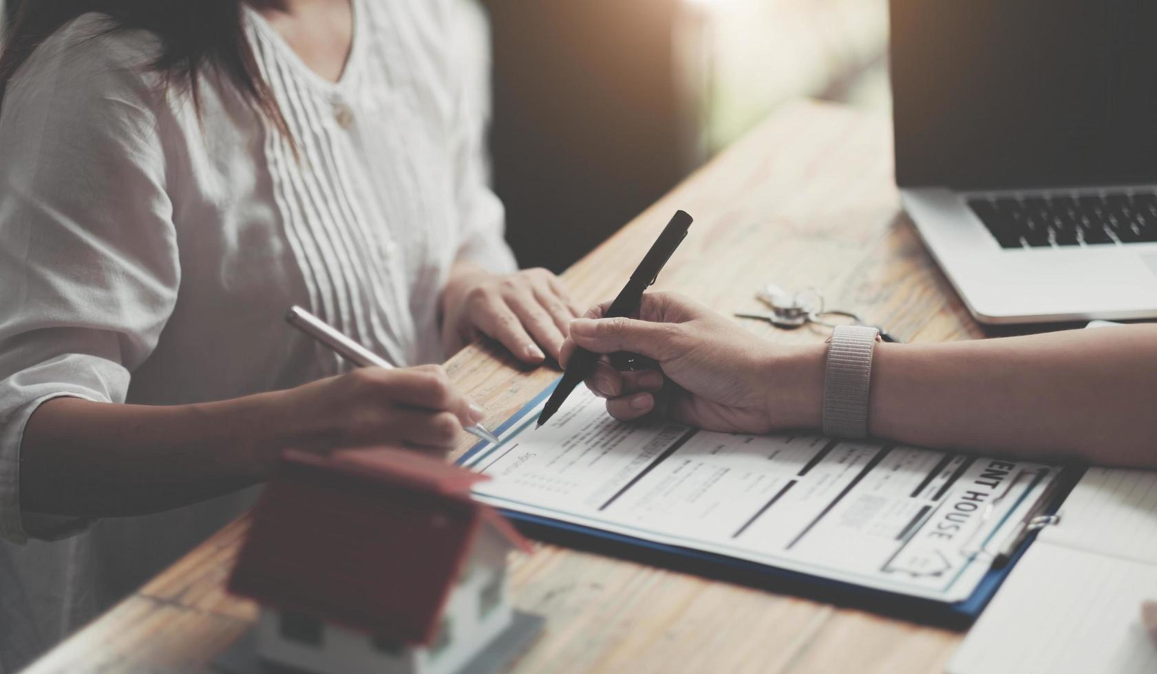 modelo de casa com agente e cliente discutindo um contrato de compra, obtenção de seguro ou empréstimo de imóvel ou propriedade. foto