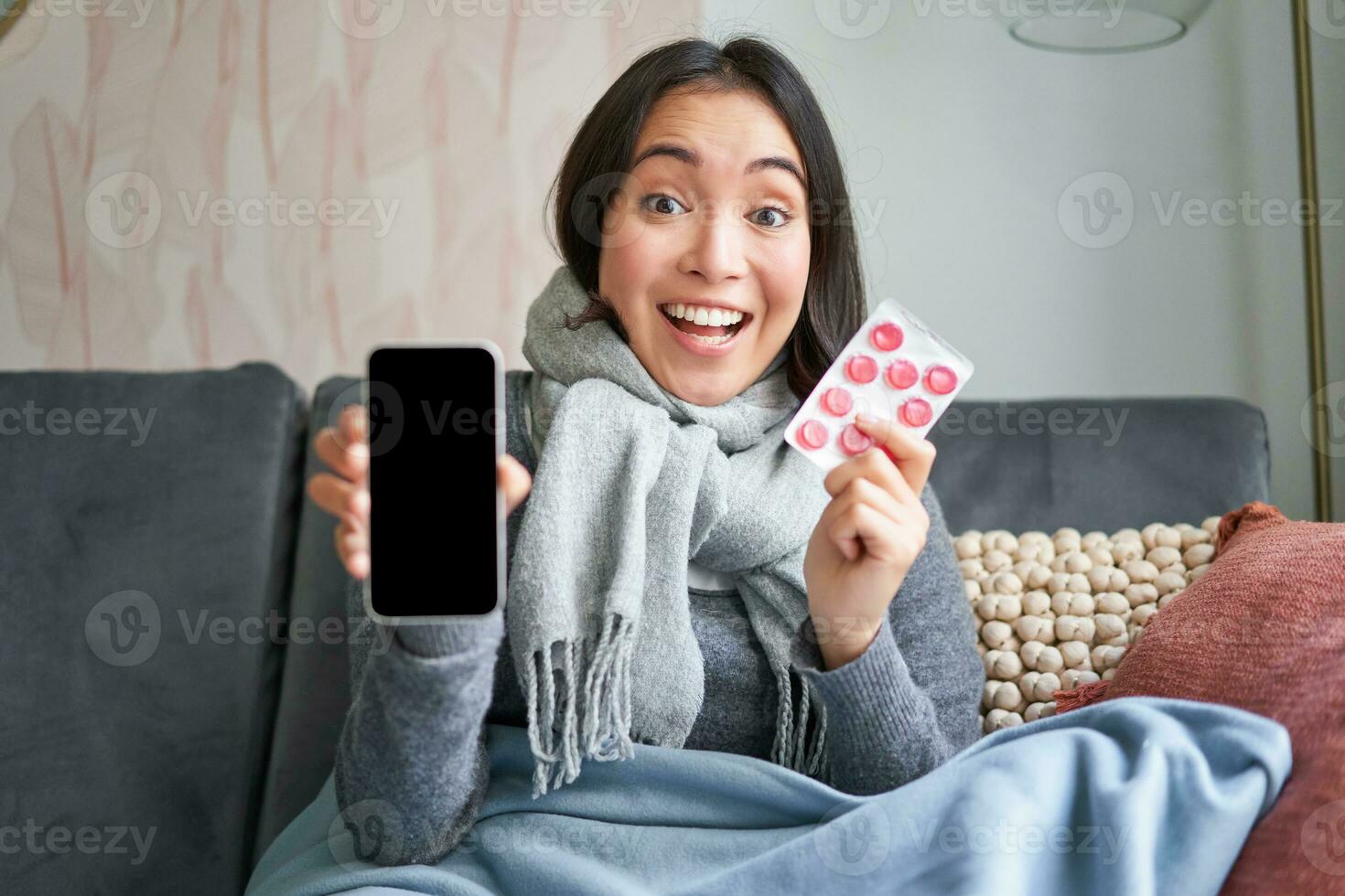 conectados médicos e assistência médica. sorridente coreano mulher mostra Móvel telefone tela e medicamento, pegando frio, ficando às casa e recomendando Smartphone gp foto