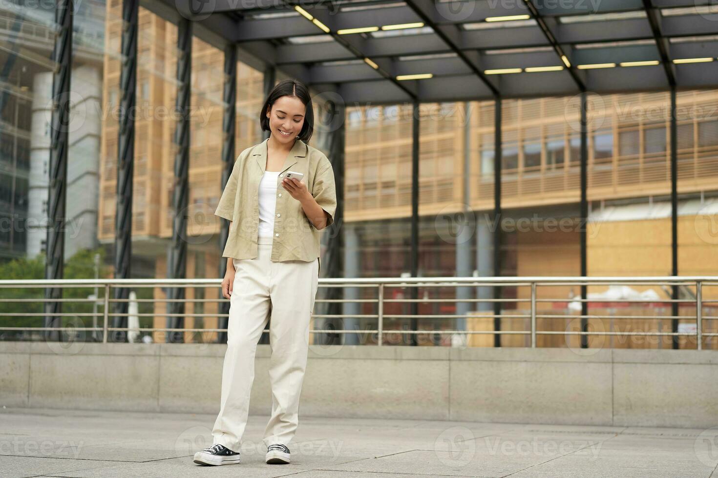 retrato do ásia fêmea modelo com Telefone. jovem coreano menina segurando Smartphone em rua, usando Telefone foto