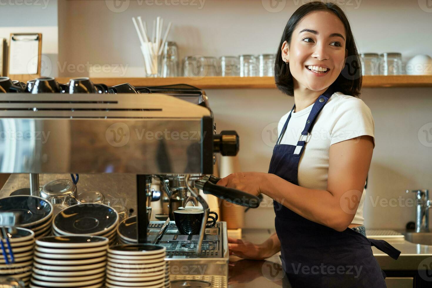 feliz sorridente barman, barista usando café máquina, preparar ordem, fazer cappuccino ou café com leite, vestindo azul avental foto