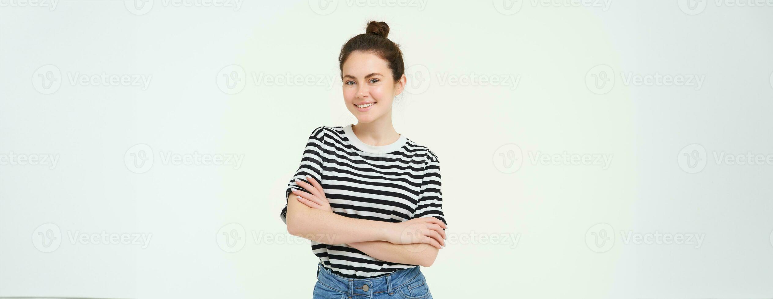 imagem do carismático jovem mulher dentro listrado camiseta e jeans, olhando confiante e feliz, sorridente às Câmera, sincero emoções, branco fundo foto