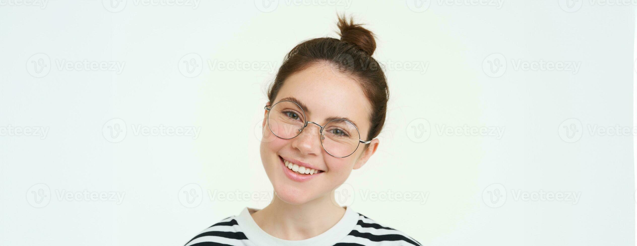 retrato do lindo jovem mulher dentro copos, vestindo óculos, sorridente e olhando feliz, tentando em Novo óculos, em pé sobre branco fundo foto