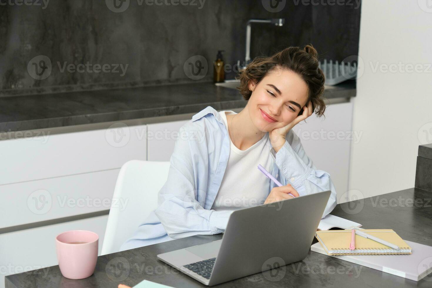 imagem do jovem mulher trabalho em computador portátil às lar, produtivo menina estudos dentro dela cozinha em computador, escuta para webinar curso foto