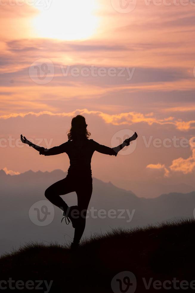 garota praticando posições de ioga nas montanhas durante uma excursão foto