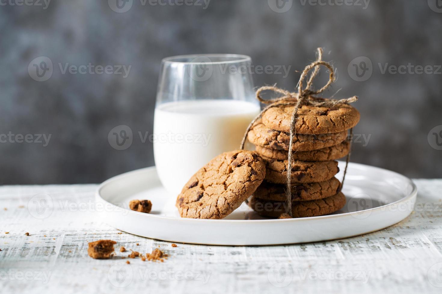 biscoitos de aveia e um copo de leite em um prato branco foto