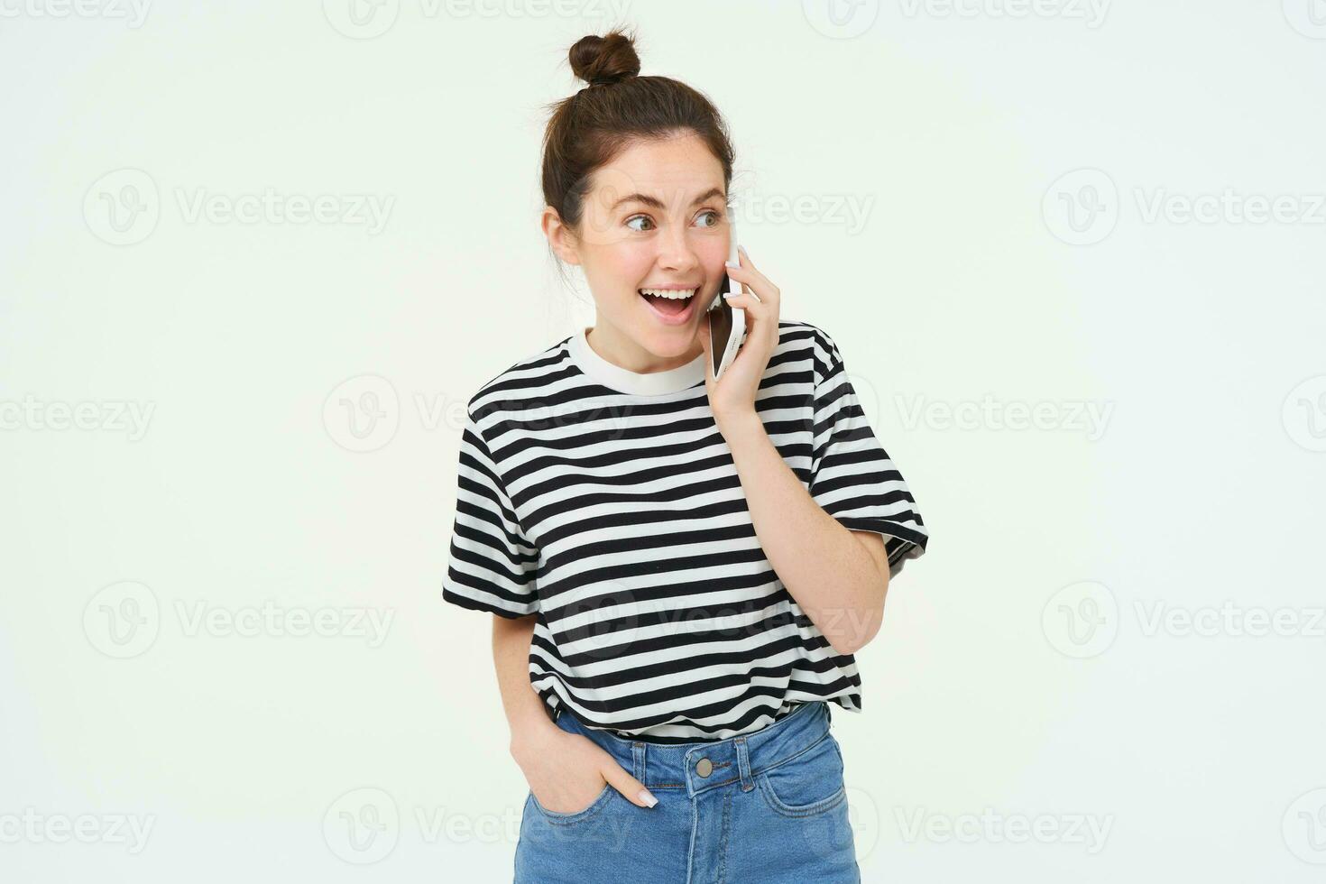 retrato do entusiasmado jovem mulher falando em Móvel telefone, conversando com amigo, reage para surpreendente notícia recebido de Telefone, branco fundo foto