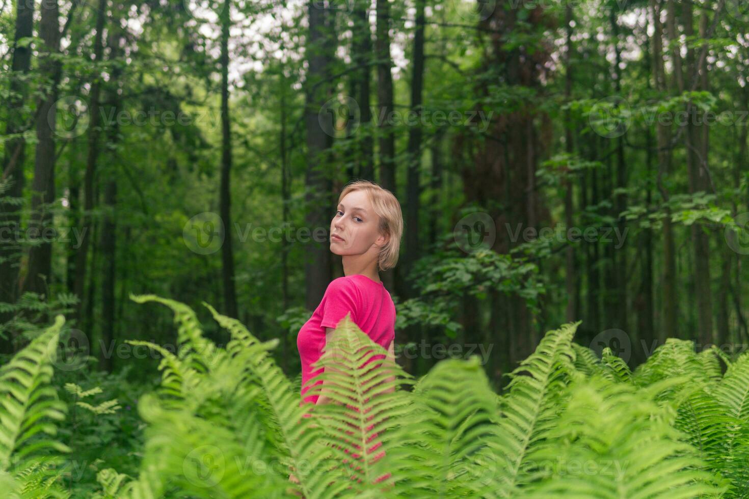 menina adolescente caminhando dentro a floresta entre samambaias foto