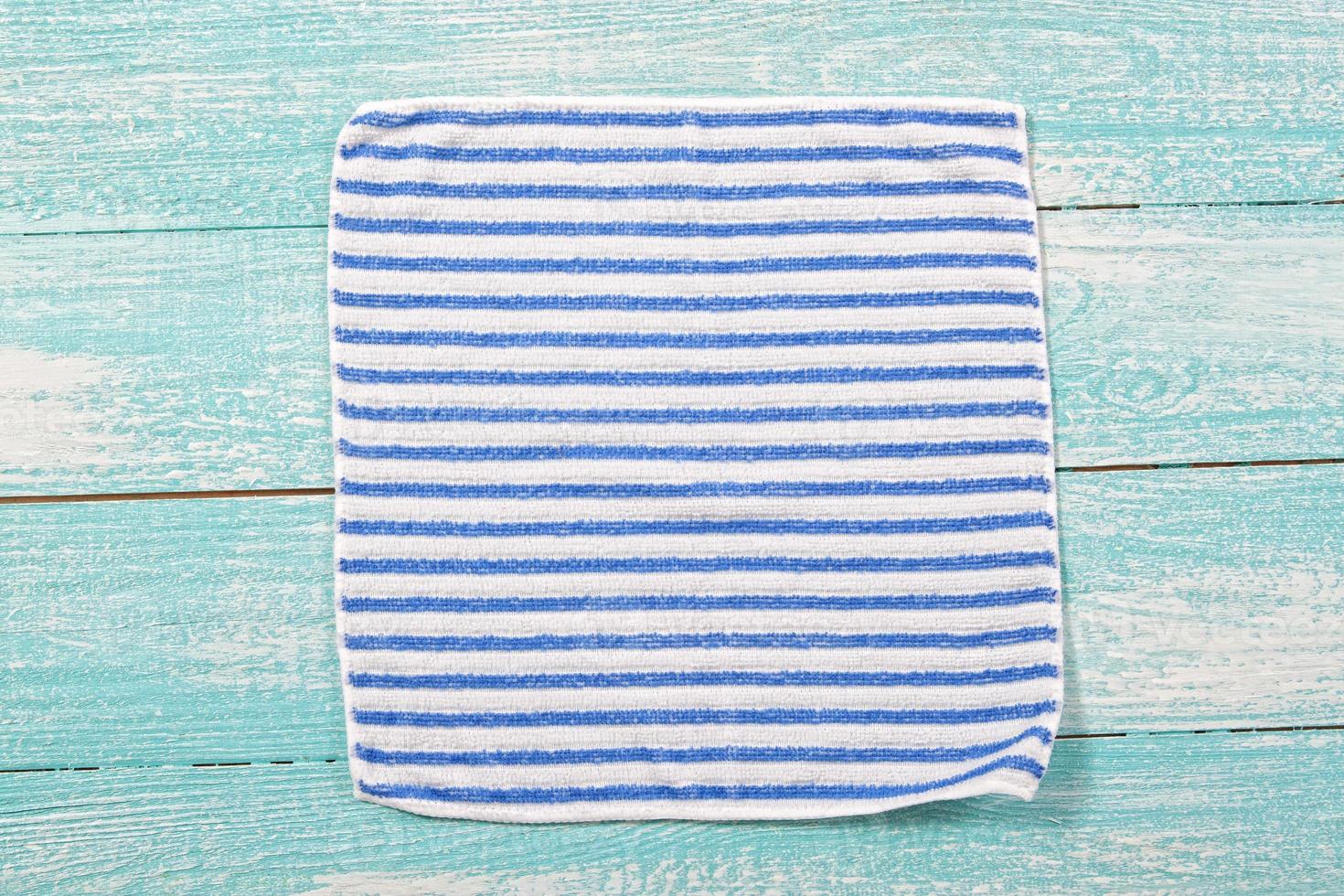 toalha guardanapo listrada na vista superior da placa de madeira azul close-up foto