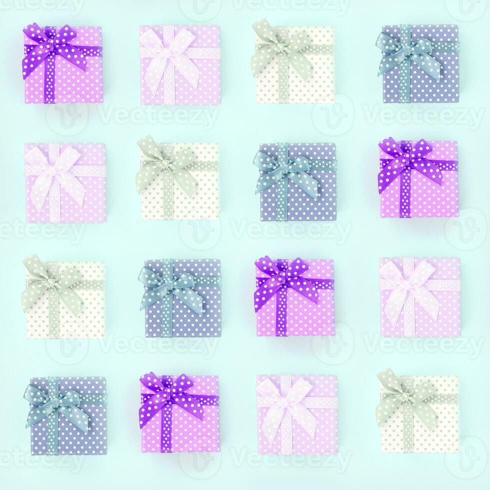 pilhas de uma pequena caixa de presente colorida com fitas encontra-se em um fundo violeta. padrão de vista superior plana lay minimalismo foto