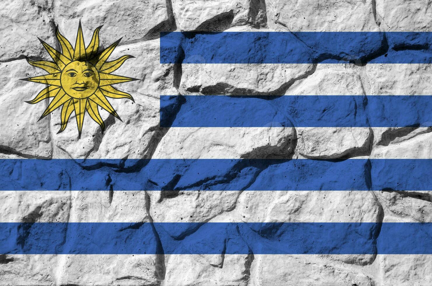 Uruguai bandeira retratado dentro pintura cores em velho pedra parede fechar-se. texturizado bandeira em Rocha parede fundo foto