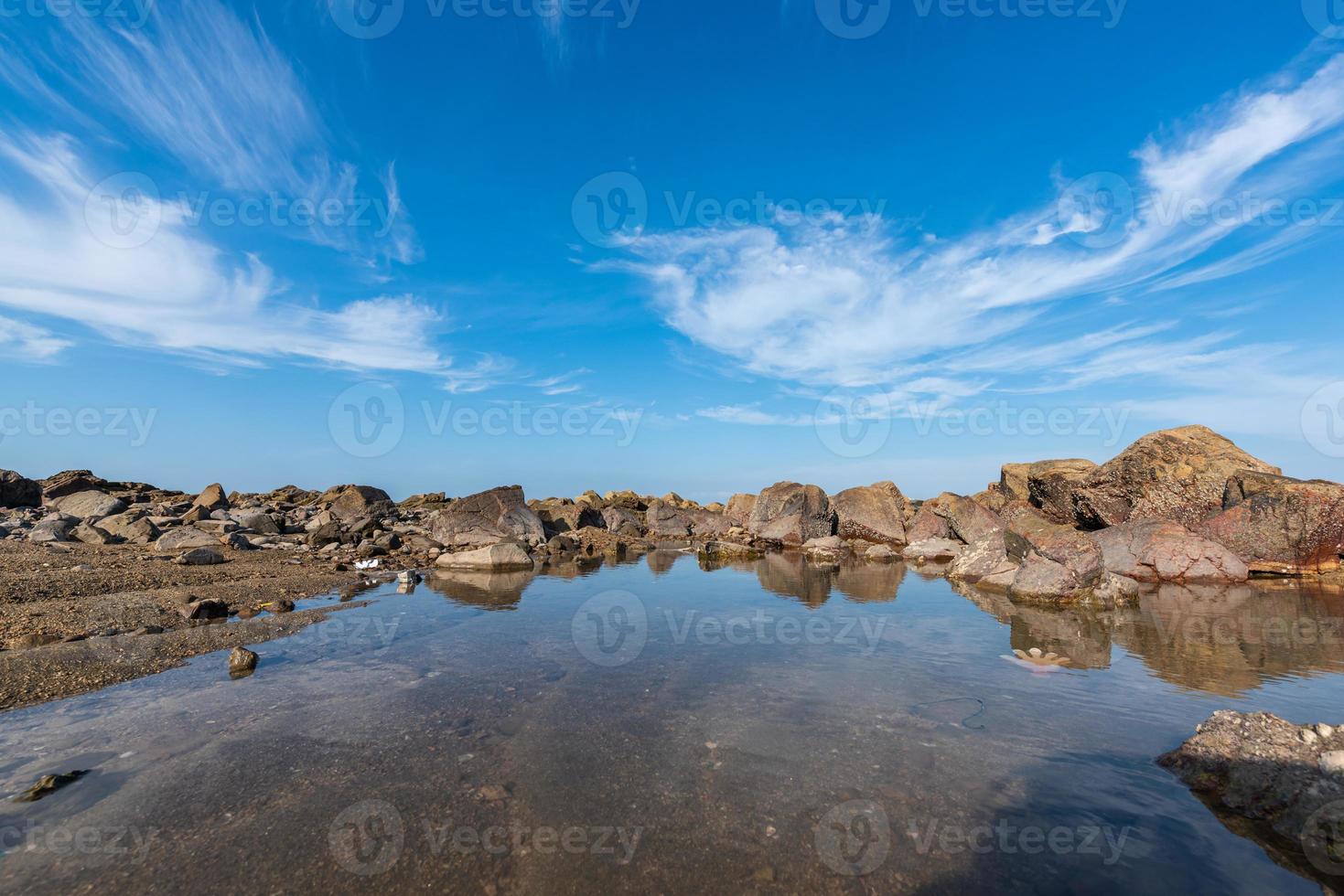 a água do mar entre os recifes à beira-mar reflete os recifes amarelos e o céu azul foto