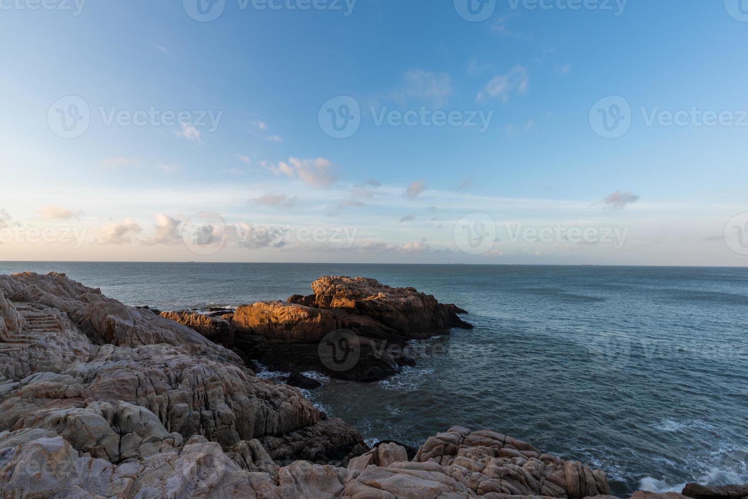 pela manhã, o sol brilha nas rochas e as ondas da praia foto